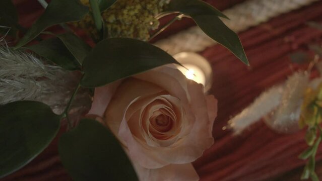 Top-down shot of a light pink rose and a tiny tea candle on a wedding reception table