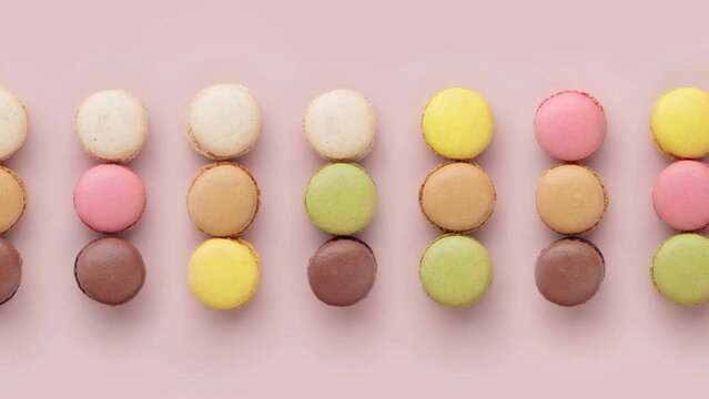 Colorful moving macaroon rows on pink background, top view video horizontal stop motion animation