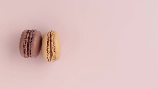 Colorful macaroons on pink background, top view video of appearance a row, horizontal stop motion animation