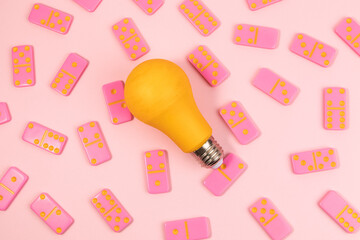 Dominoes and a light bulb on top view,Pink background.Flat lay