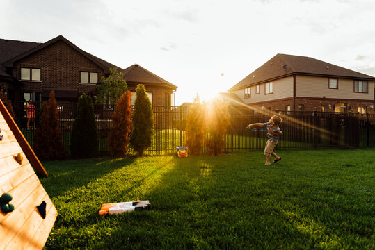 Boy throwing ball while playing at backyard
