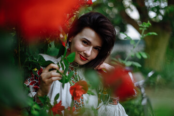 A girl in a national costume among blooming roses