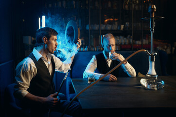 Stylish gangsters smoking hookah in bar having business meeting