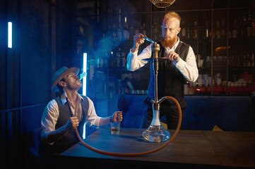Portrait of retro guys smoking hookah pipe in bar