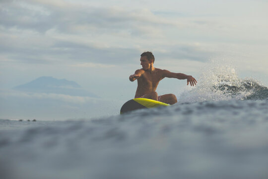 Man surfing in sea against cloudy sky