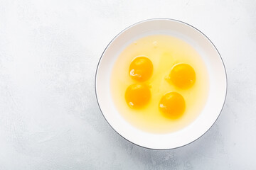 Raw eggs, top view of four raw eggs yolk in bowl on white background