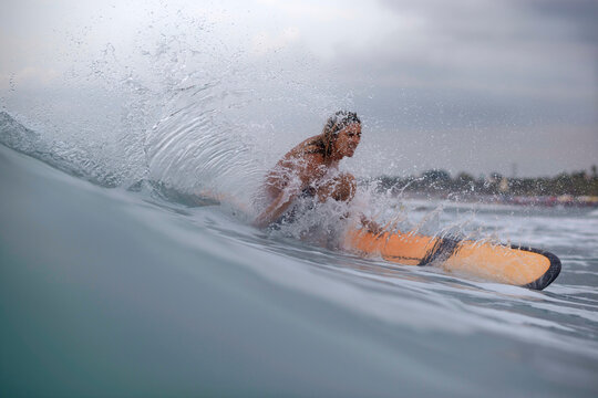 Man surfing in sea against cloudy sky