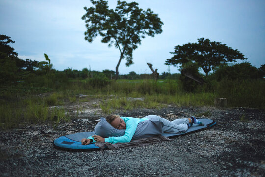 Woman sleeping on bag against sky