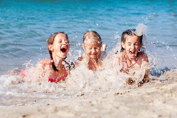 Happy Children Having fun Playing with Sea Waves on Sandy Beach. Funny Kids Swiming and Splashing....