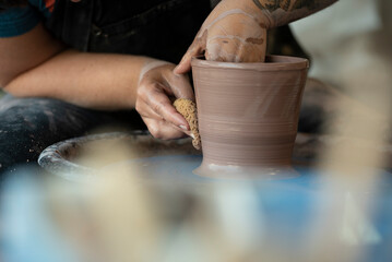 Hands crafting a pot on pottery wheel