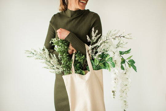 Happy Young Woman Holding Cloth Bag of White and Green Flowers