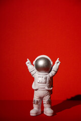 Plastic toy astronaut on colorful red background Copy space. Concept of out of earth travel, private spaceman commercial flights missions and Sustainability