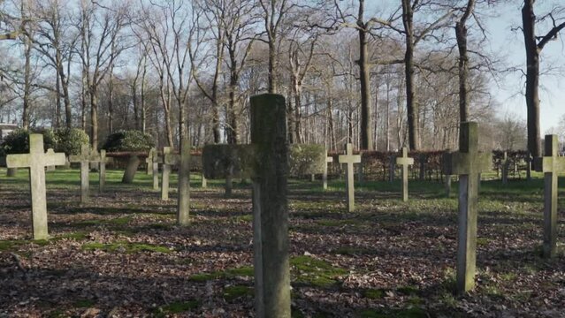 Stone crosses on the tombs of a cemetery during the daytime, Low angle view of unmarked and anonymous tombs in the woods