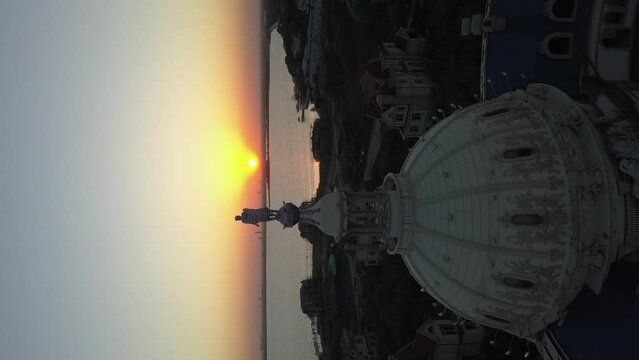 Sunset aerial retreats from abandoned dome building by lake shore