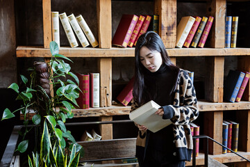 Candid lifestyle portrait of happy Stylish Young Asian beautiful female student in library with...