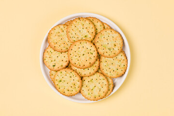 round crispy biscuits in plate on yellow background.