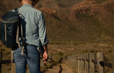 Adult man in cowboy hat walking on dirt road