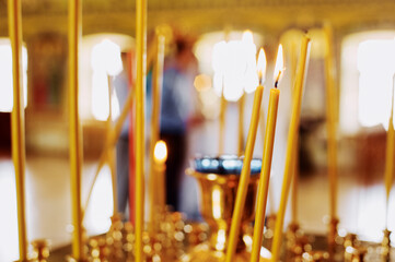 Burning church candles in a gilded candlestick in a temple.