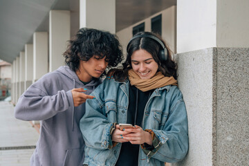 Obraz premium young teenagers looking at mobile phone in the street