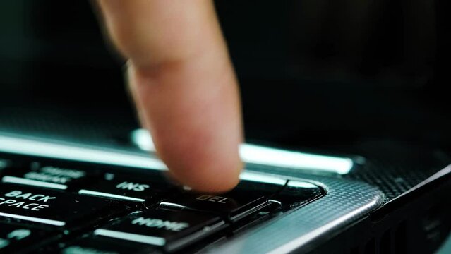 Finger of the computer user, he presses the delete button on the computer keyboard.	