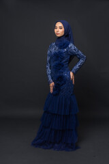 Naklejka premium A teenager model use blue dress. She's pose in the studio indoor. She's pose in dark gray background with elegant pose. She's look like beautiful and graceful 