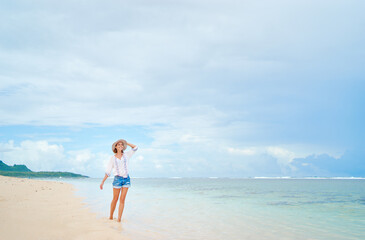 Vacation on the seashore. Young woman walking on the beautiful tropical white sand beach.