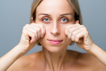 Skin care. Blonde woman with beauty face facial massage. No makeup. Grey background.