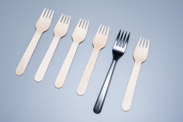 Plastic and wooden forks on a gray background. Save the ecology.