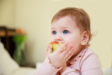 Little cute girl eats an apple. Healthy food concept. Vitamins in natural products. Child 1 year...