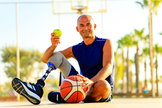 latin man with prosthetic leg sitting on coart and eating an apple
