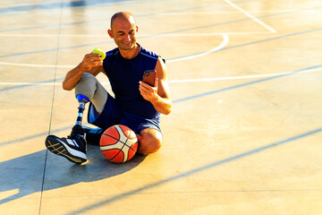 disabled person with leg prosthesis playing basketball in tropical sea side at sumset time eating an apple
