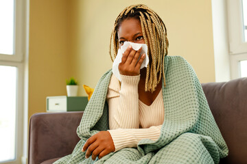 afro american woman covered with blanket blowing running nose