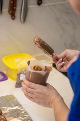 woman confectioner dips marshmallows on a stick in chocolate. home bakery concept.