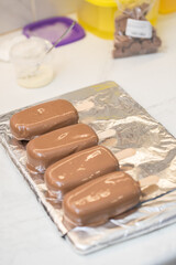 woman confectioner dips marshmallows on a stick in chocolate. home bakery concept.