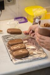 woman confectioner dips marshmallows on a stick in chocolate. home bakery concept.