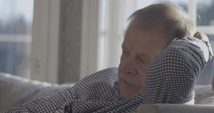 Close Face Portrait Of talking SenRetirement ior Man in deep serious discussion On Sofa At Home