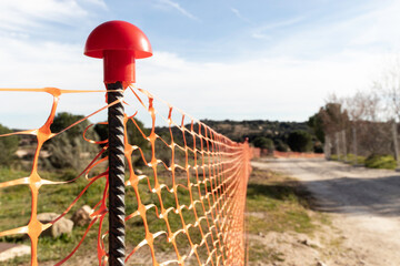 close up of an orange fence with a post sticking out of it. Construction site barrier or protective...