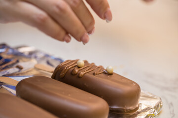 woman confectioner decorates marshmallows in chocolate on a stick. home bakery concept.