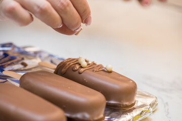 woman confectioner decorates marshmallows in chocolate on a stick. home bakery concept.