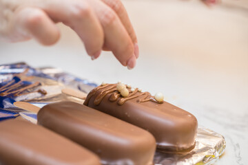 woman confectioner decorates marshmallows in chocolate on a stick. home bakery concept.