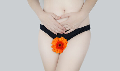 Virginity. Menstruation. Critical days. Concept photo. The girl holds a flower in the crotch area, symbolizing the hymen, critical days and gynecological problems. - obrazy, fototapety, plakaty