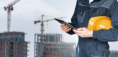 Engineer with a digital tablet on the background of a building under construction