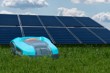 Lawnmower robot mows grass between solar panels