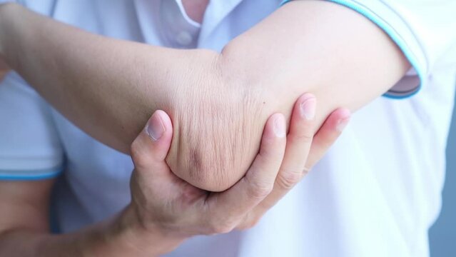 man touching the elbow with elbow pain And he relieves pain with massage. Health and healing concept.