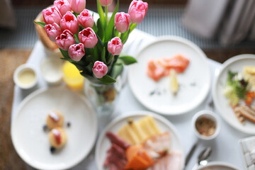 Festive breakfast with pink tulips. Breakfast in the hotel room. Birthday morning. Breakfast in bed. Mothers Day. Pink flower