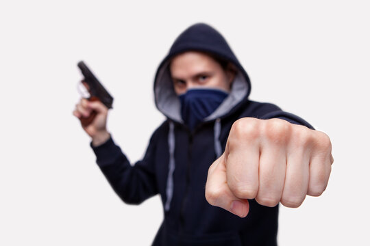 The male criminal in action of attacking with hand gun pointing gun to target in front. Isolated on gray background. The concept of crime for presentation slide.