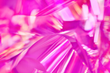 Close-up of ethereal bright neon pink, magenta, orange holographic metallic foil background....