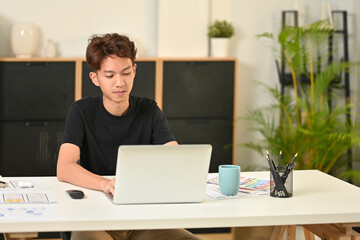 Young male web developer planning application template layout framework for mobile phone at office