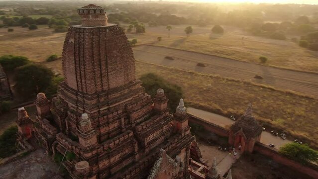 Drone panning shot of the high Myauk Guni and Dhammayangyi Temple in Myanmar during a colorful sunset.