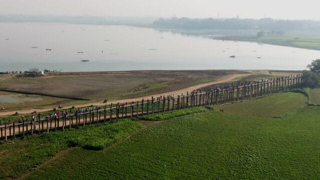 People walking over the U-Bein Bridge in Mandalay in Myanmar. Drone panning shot